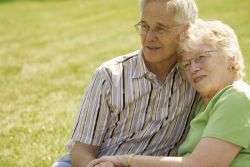 זוג מבוגר-יושב מחובק על הדשא-ביטוח סיעודי במתן שרותי רווחה